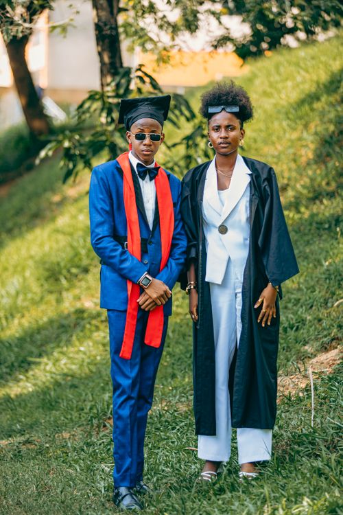 Free Two graduates standing outdoors in caps and gowns, celebrating their achievement. Stock Photo