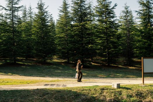 A woman enjoying an outdoor walk on a serene tree-lined path in the forest.