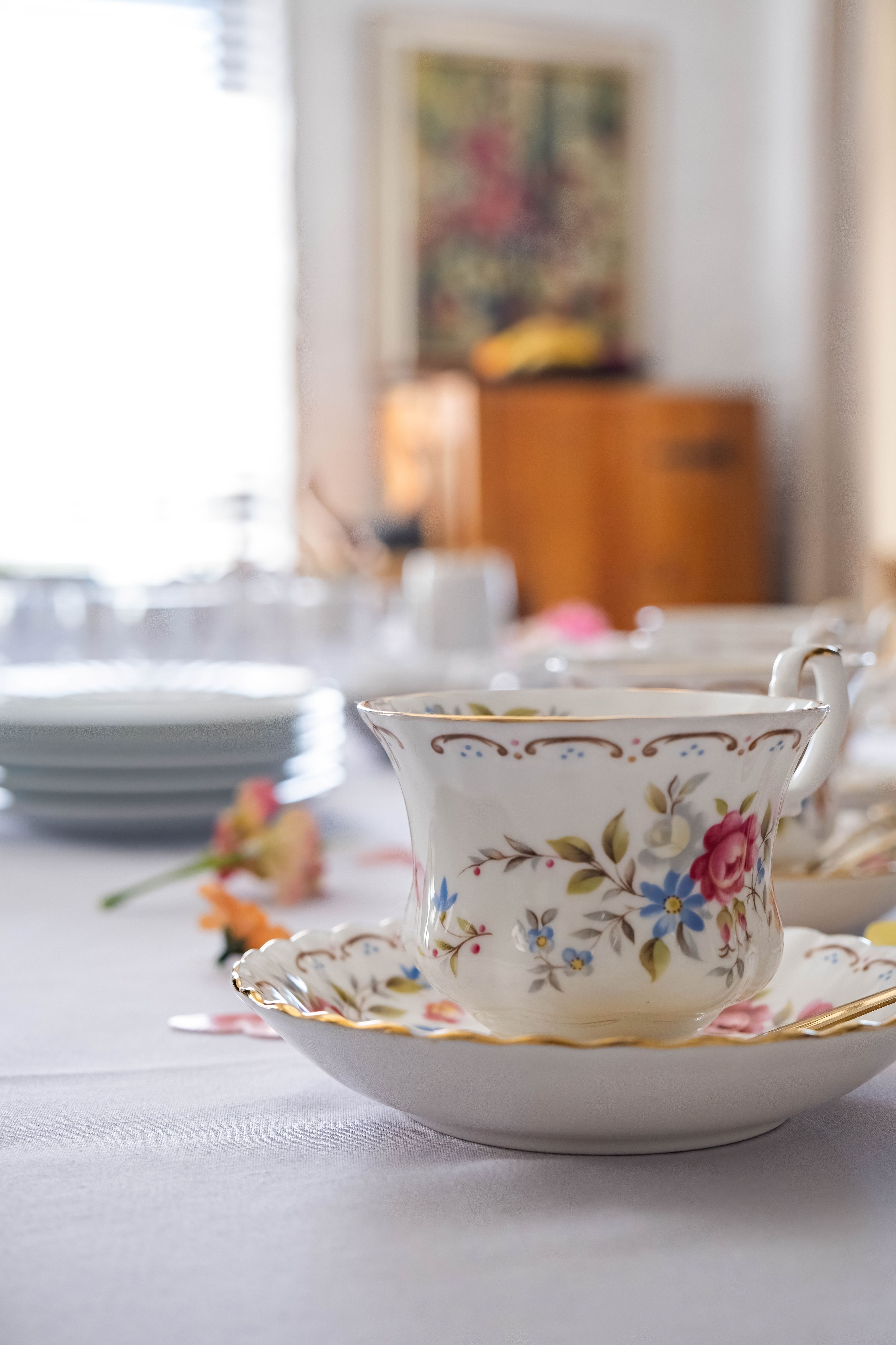 Gros plan sur une tasse de thé fleurie posée sur une table dressée, lumière du jour