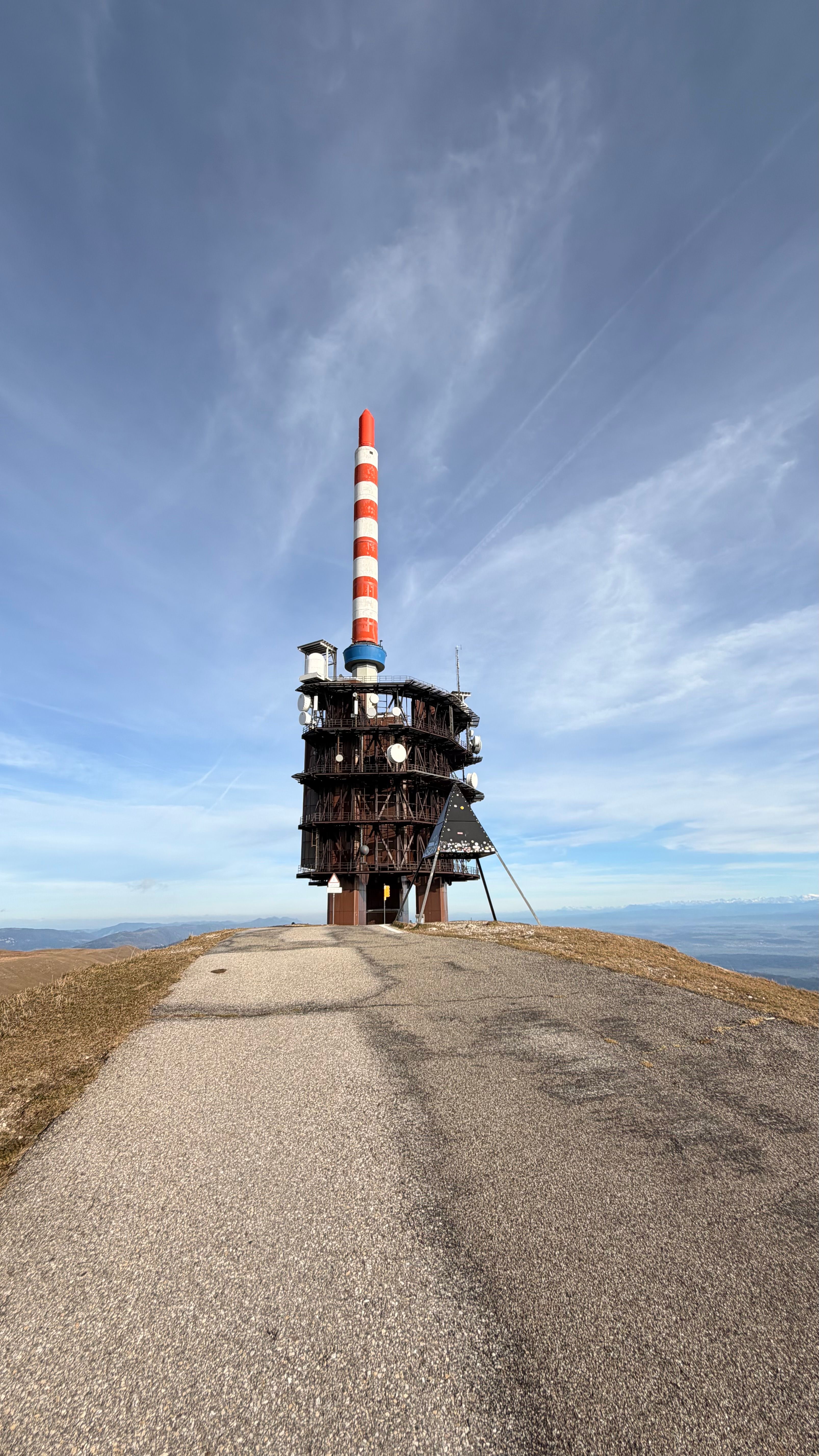 A broadcast tower on Chasseral peak in the Jura Mountains under a clear blue sky.