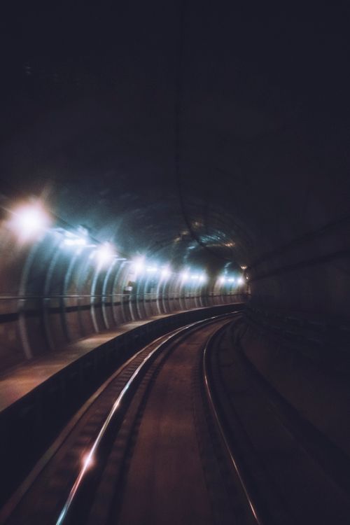 Free Moody view of a curved metro tunnel with rail tracks in Copenhagen, Denmark. Stock Photo