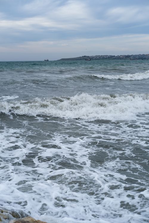 Free Waves gently crashing on the sandy shores of Büyükçekmece, İstanbul, under a cloudy sky. Stock Photo