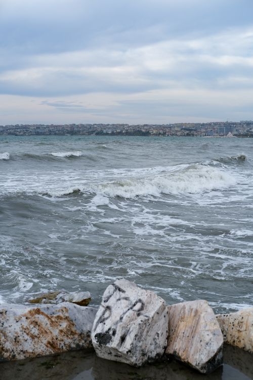 Free Waves crashing against rocks with a distant city view in Büyükçekmece, Istanbul. Stock Photo