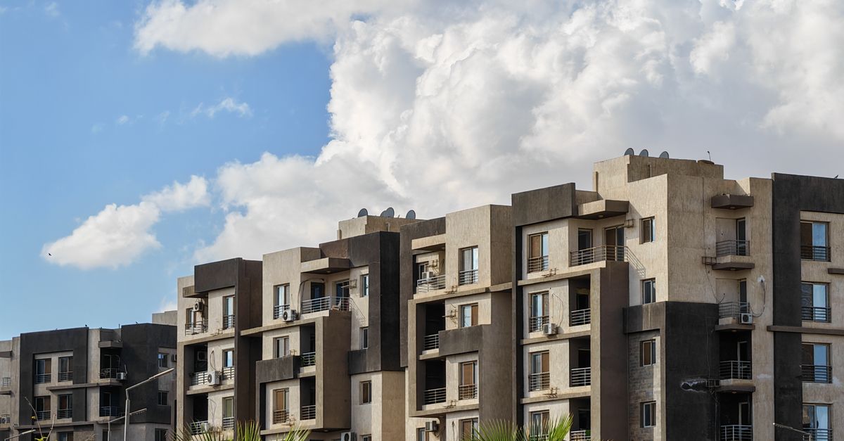 Contemporary urban apartment buildings under a bright blue sky with palm trees.