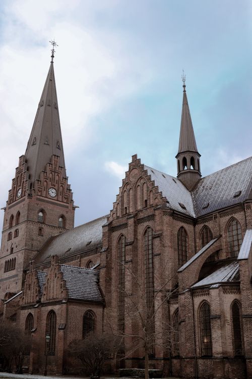 Free Majestic Gothic church in Malmö, Sweden, showcasing Nordic architecture with snow-capped roofs under a clear sky. Stock Photo
