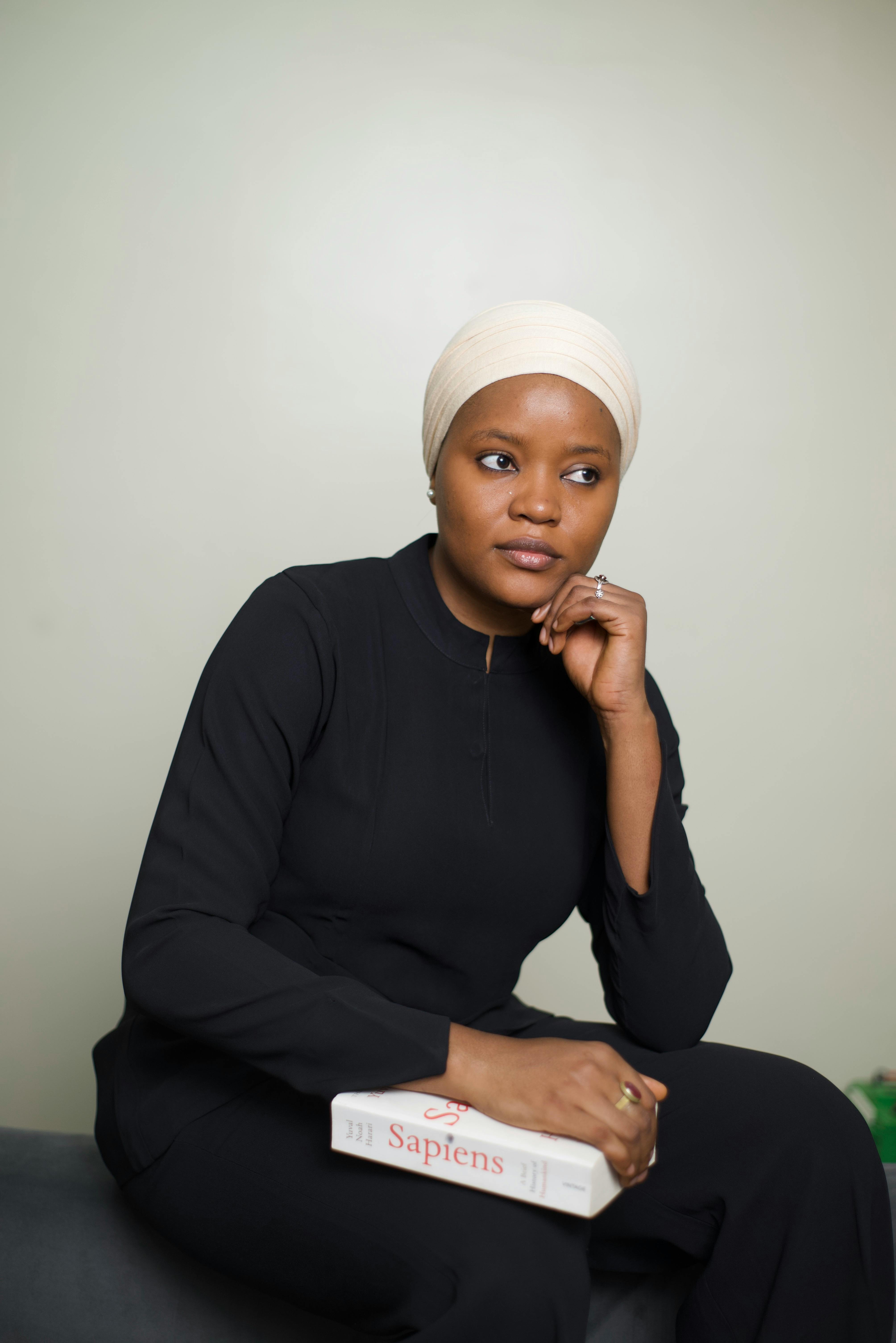 Portrait of a thoughtful Muslim woman holding a book indoors, emphasizing education and reflection.