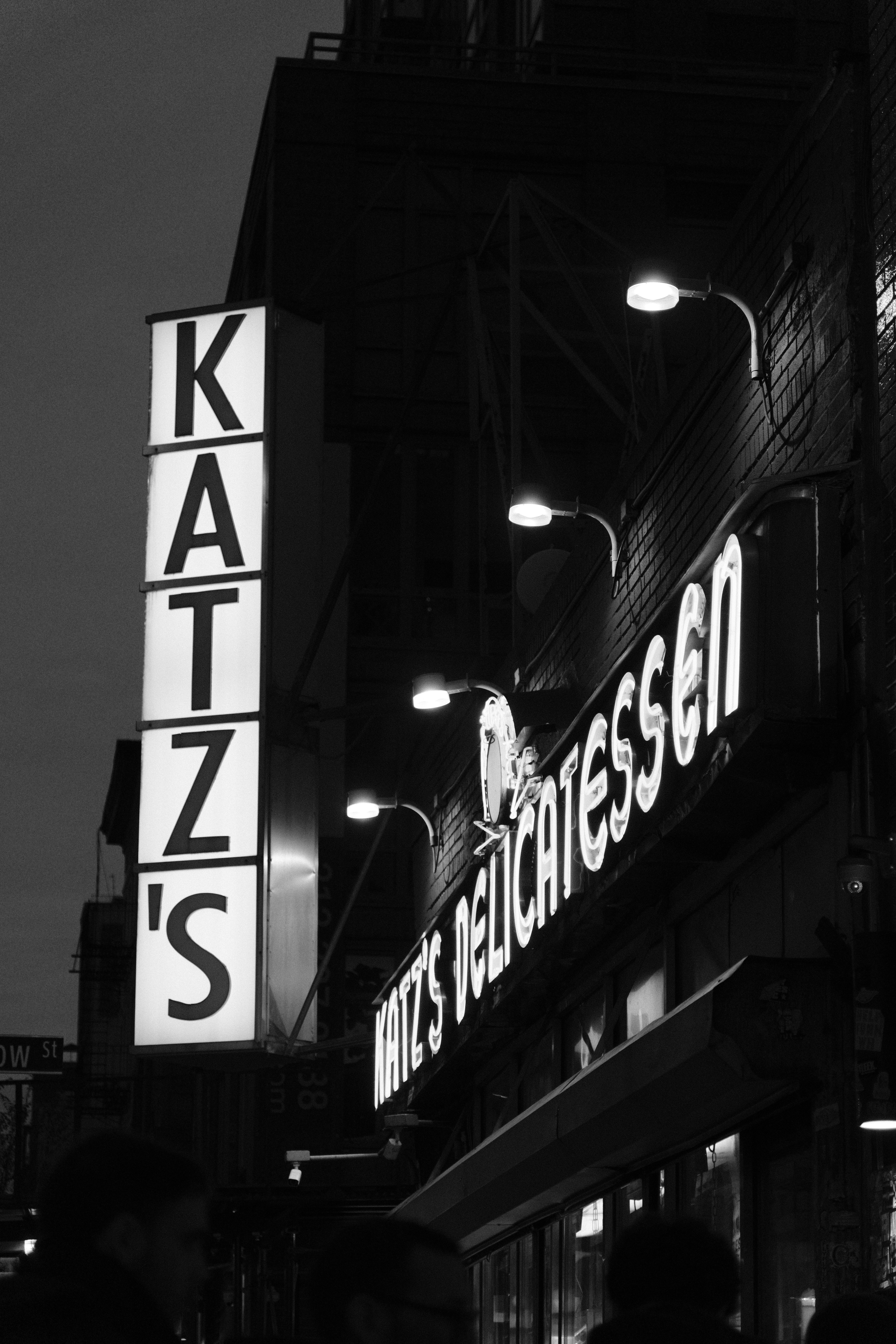Black and white photo of Katz's Delicatessen signage in New York City at night.