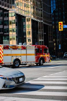 Red fire truck navigating a busy intersection in Toronto with modern skyscrapers in the background.