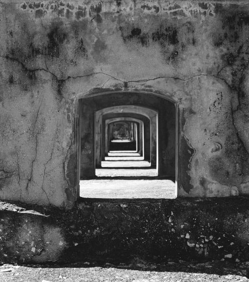 Free Black and white view of repeating arches in an aged tunnel wall, showcasing architectural depth. Stock Photo