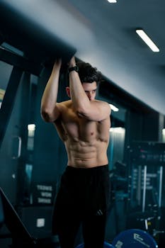 Young athletic man working out in a gym, showcasing muscular physique with focused expression.