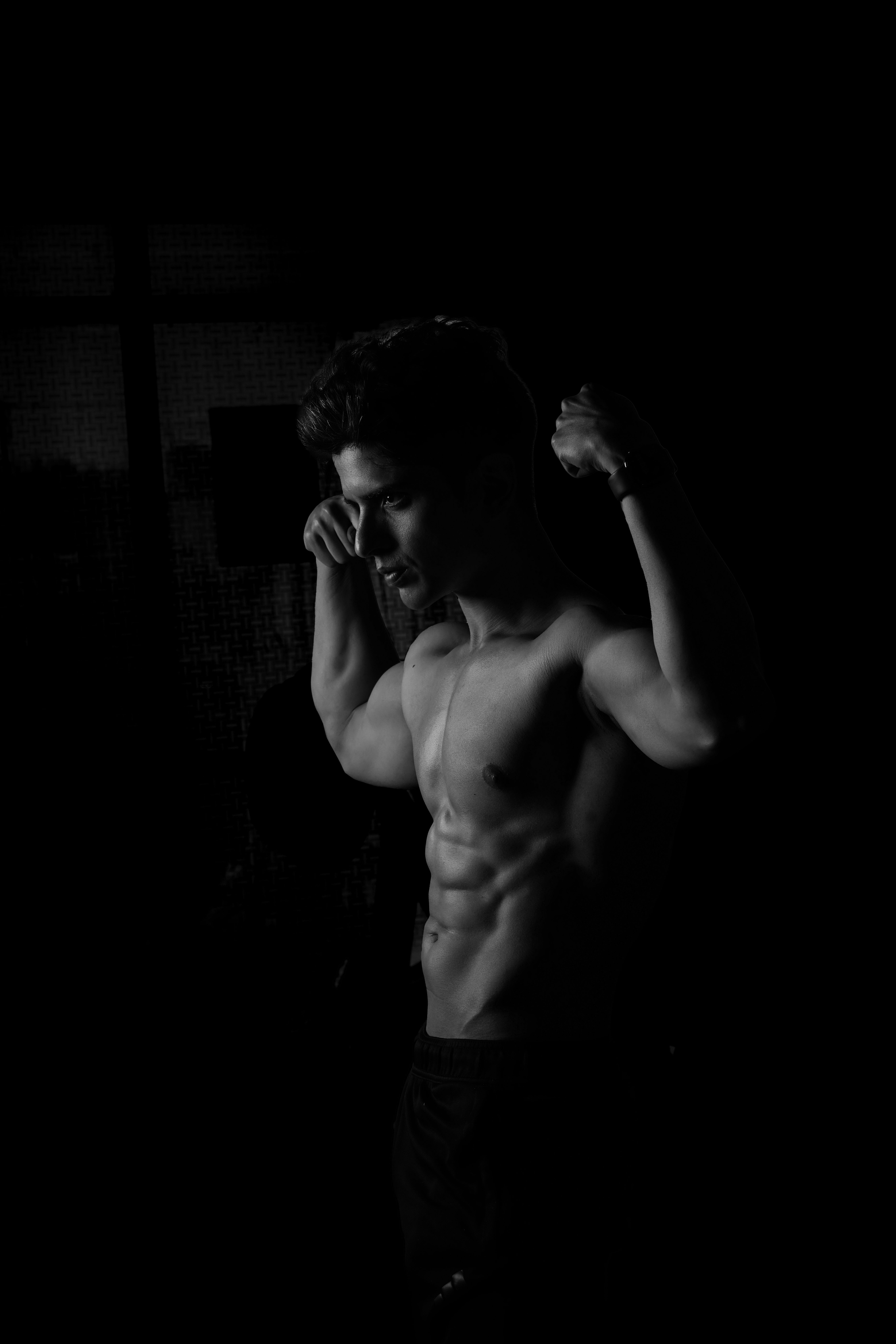 A muscular young man striking a pose in a dark, moody gym setting.