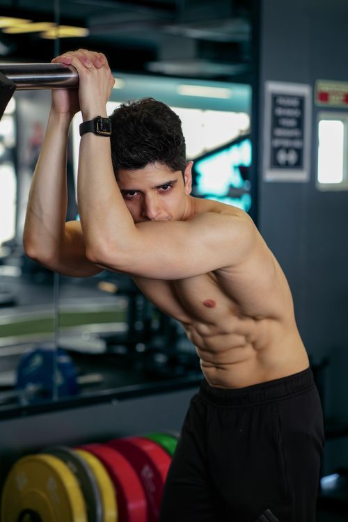 Free Athletic man showcases muscular physique in a modern gym, emphasizing fitness and strength. Stock Photo