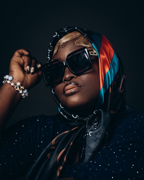 Free Stylish woman in sunglasses and scarf gracefully posed for a fashion portrait. Stock Photo