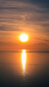 Golden sunset reflecting on calm sea with vibrant sky.