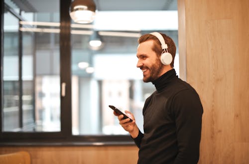 Man Wearing Black Long Sleeve Shirt While Holding Black Smartphone