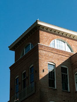 A red brick building with arched windows under a clear blue sky, showcasing architectural detail.