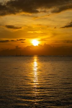 Beautiful ocean sunset with golden reflections over calm waters, creating a serene and tranquil scene.