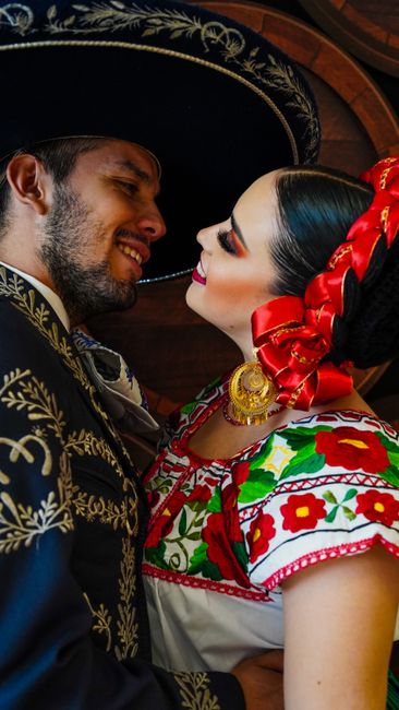 A couple shares a romantic moment in colorful traditional Mexican clothing.