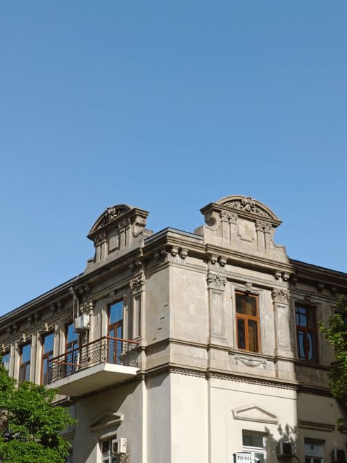 Free Close-up of a historic European-style building with ornate architectural details under a clear blue sky. Stock Photo