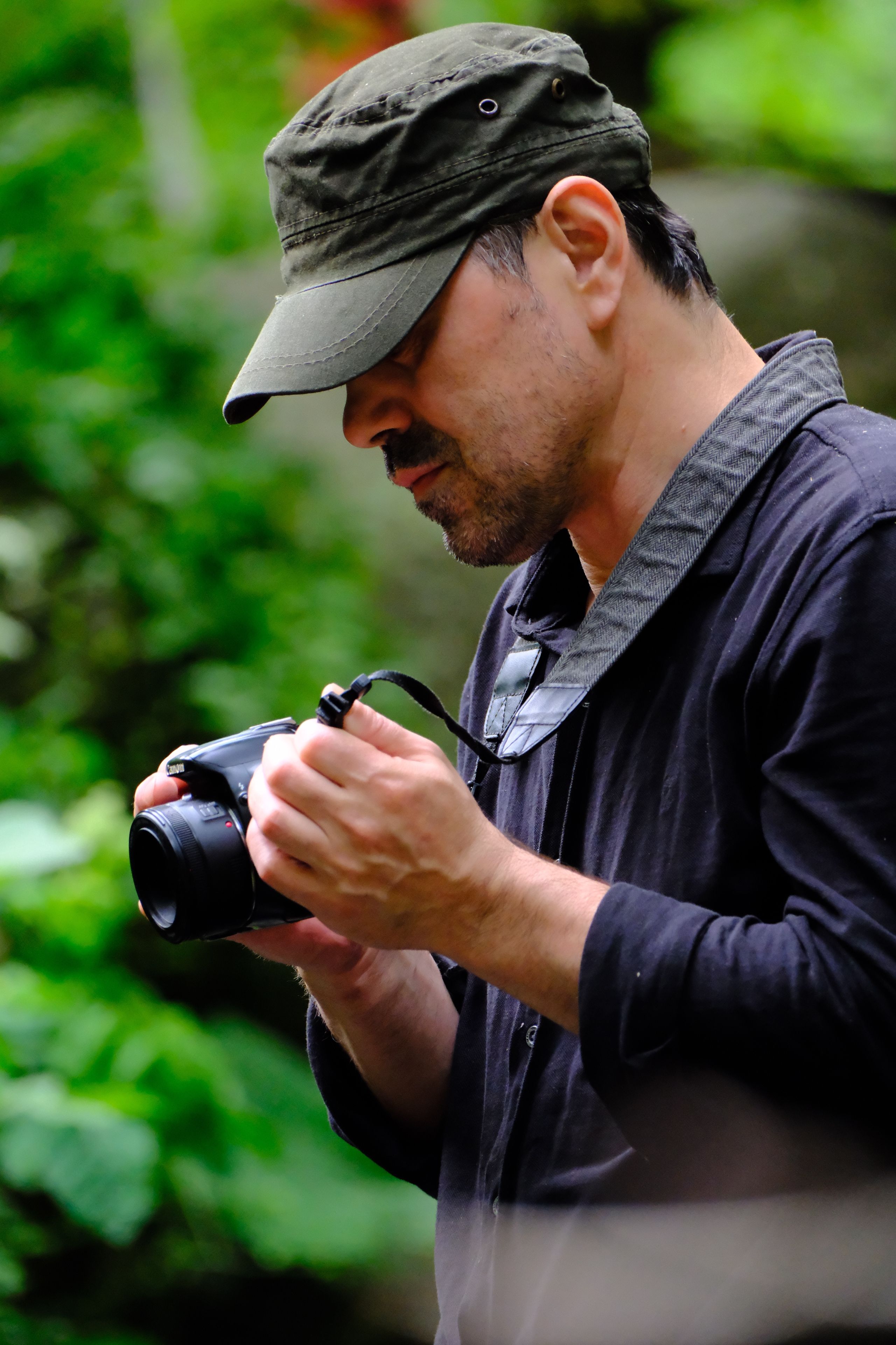 A male photographer with a camera focused in an outdoor environment.