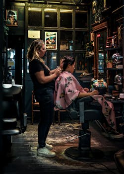 A hairstylist carefully tends to a client's hair in a warm and cozy salon setting.