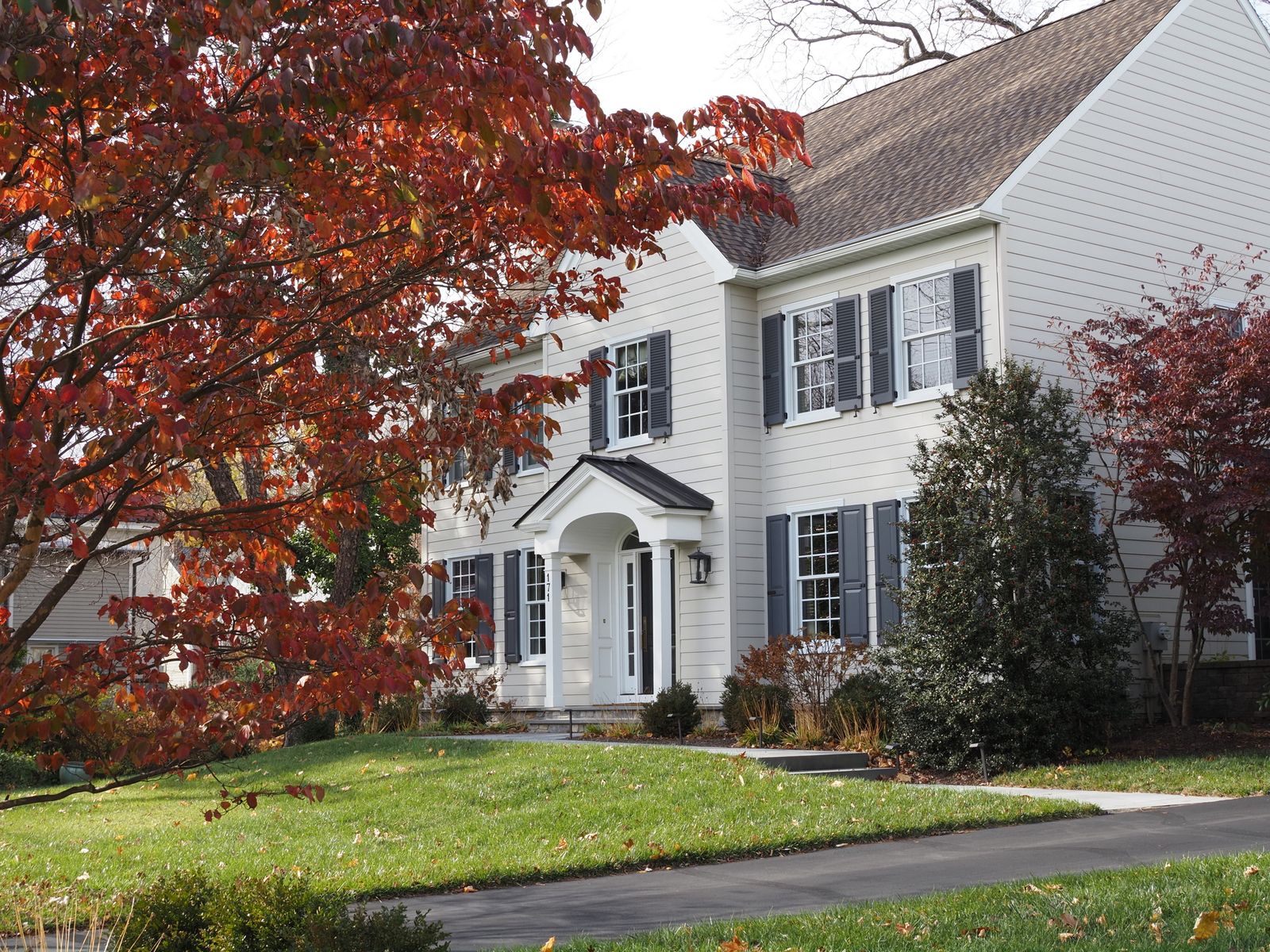 Two-story brick colonial home with black shutters and a covered entry on a tree-lined lot, Century Hill, Naperville IL