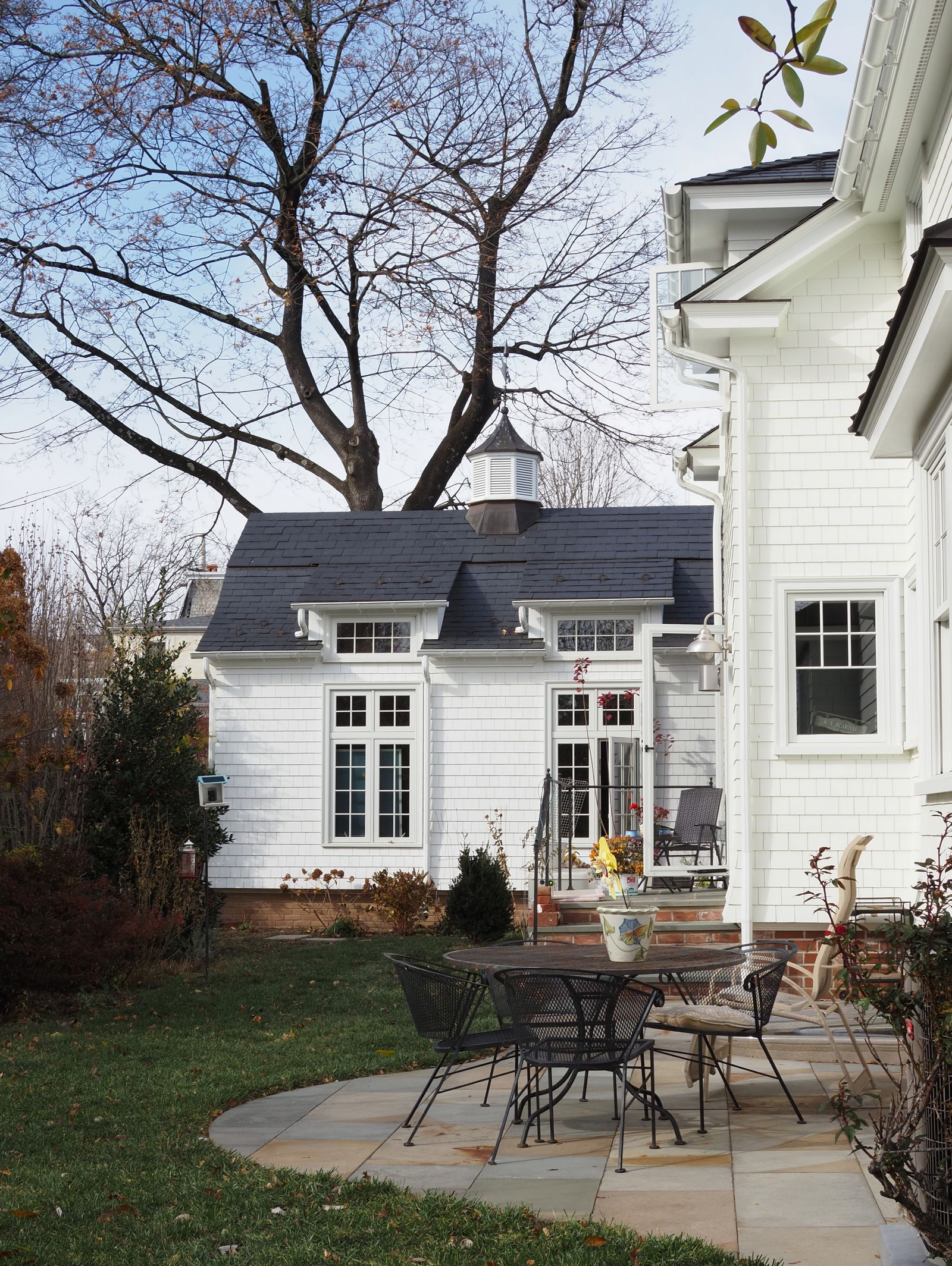 White cottage with stone dining patio and fall foliage
