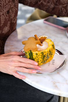 A pumpkin spice latte served in an edible pumpkin mug with gingerbread cookie and cinnamon sticks, shot in İstanbul.