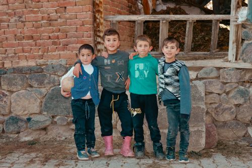 Free Group of boys posing cheerfully outside against a rustic brick and stone wall. Stock Photo