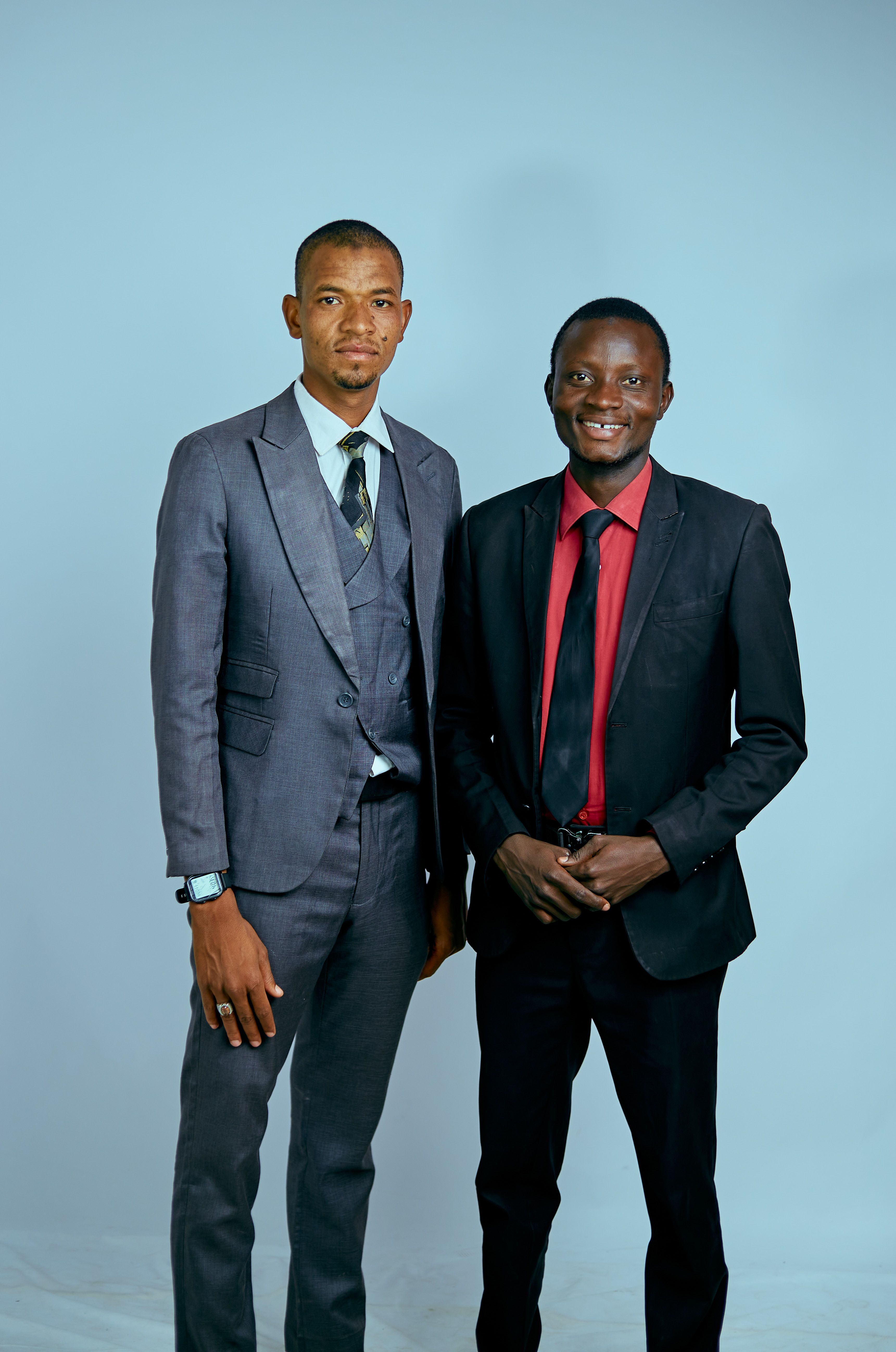 Two business professionals in formal suits posing against a plain background.