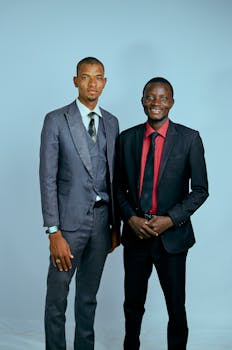 Two business professionals in formal suits posing against a plain background.