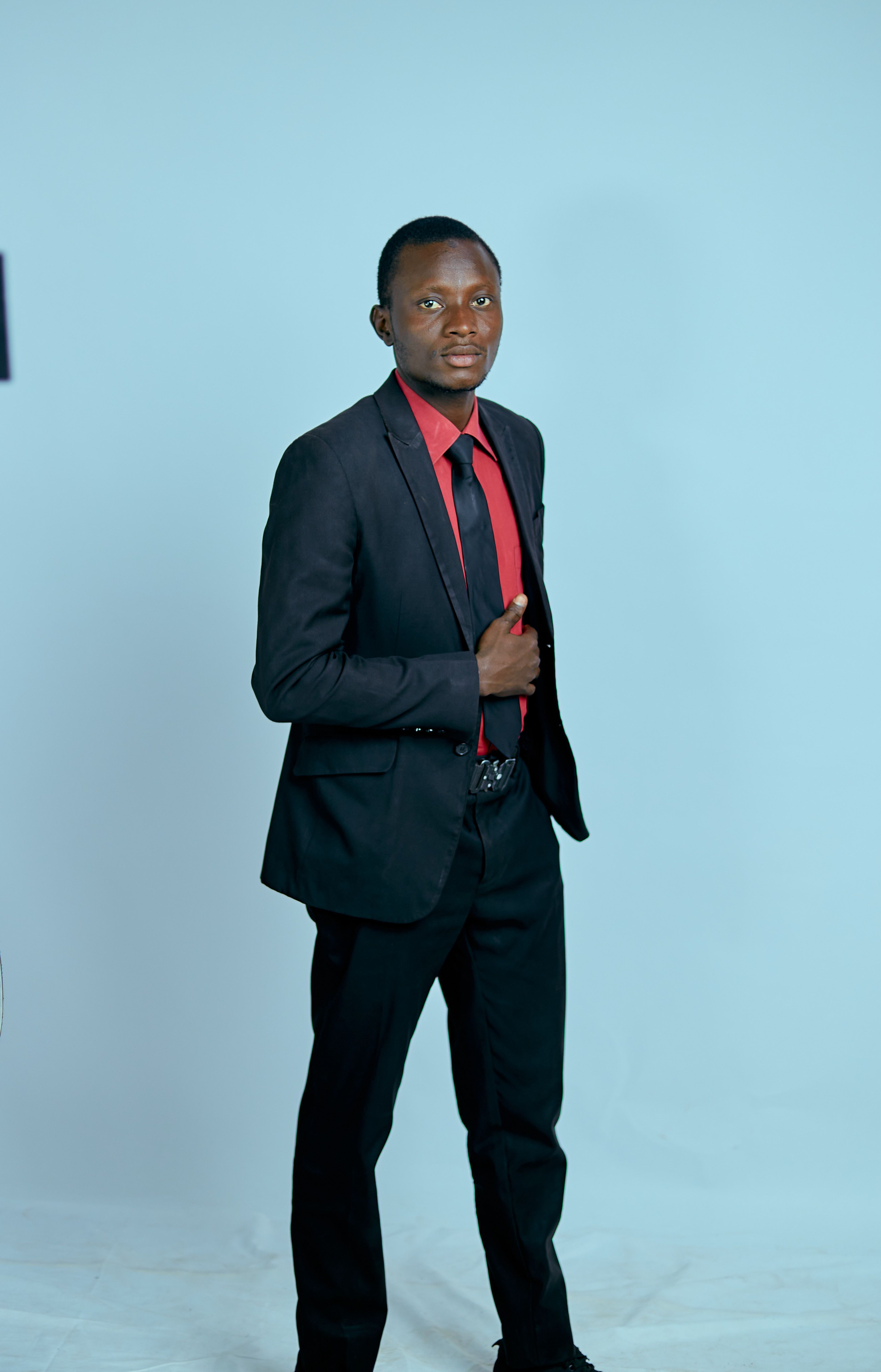 Young African businessman posing confidently in formal attire against a plain background.