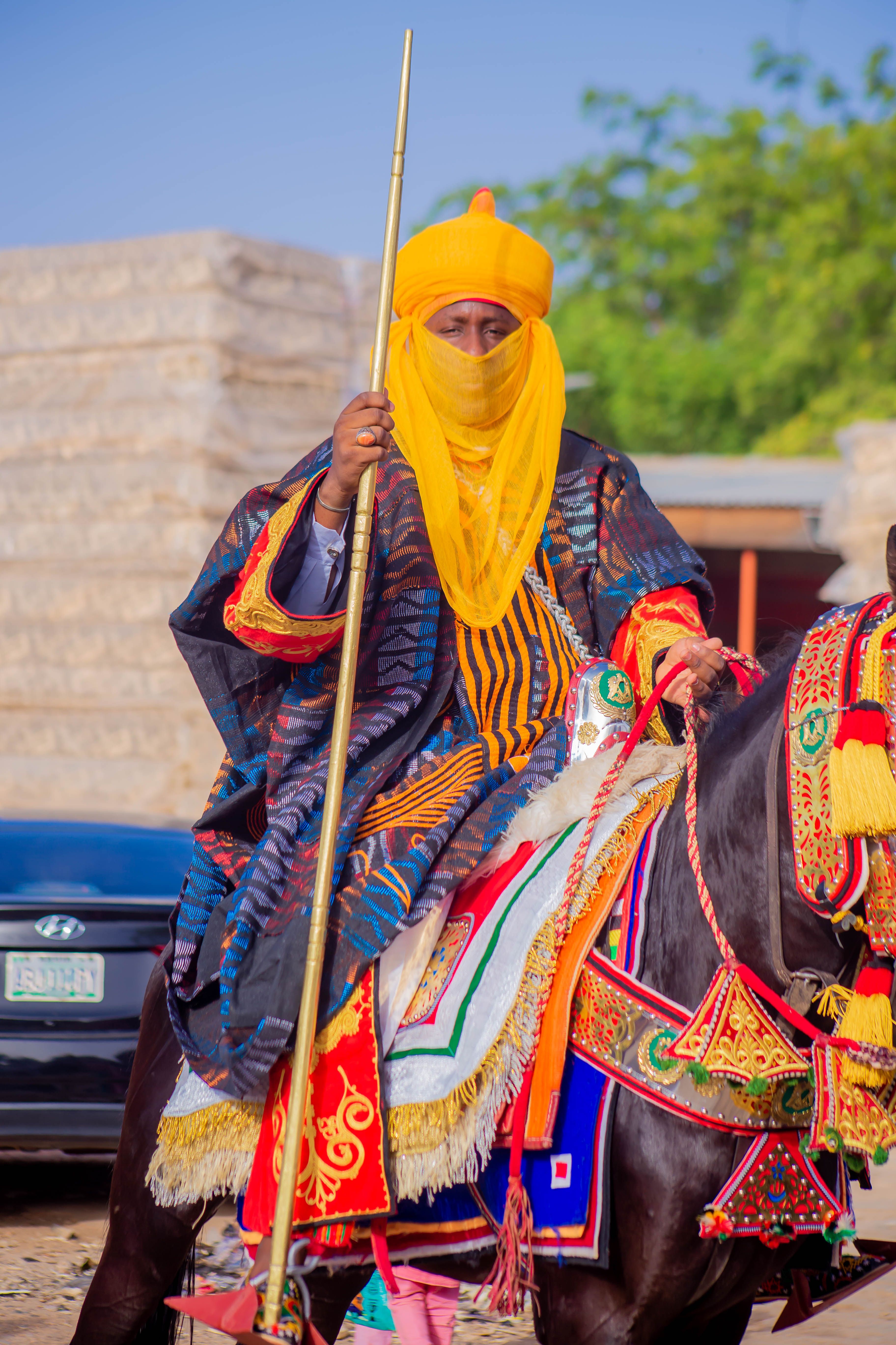 Regal figure in traditional attire rides a decorated horse, showcasing cultural heritage.