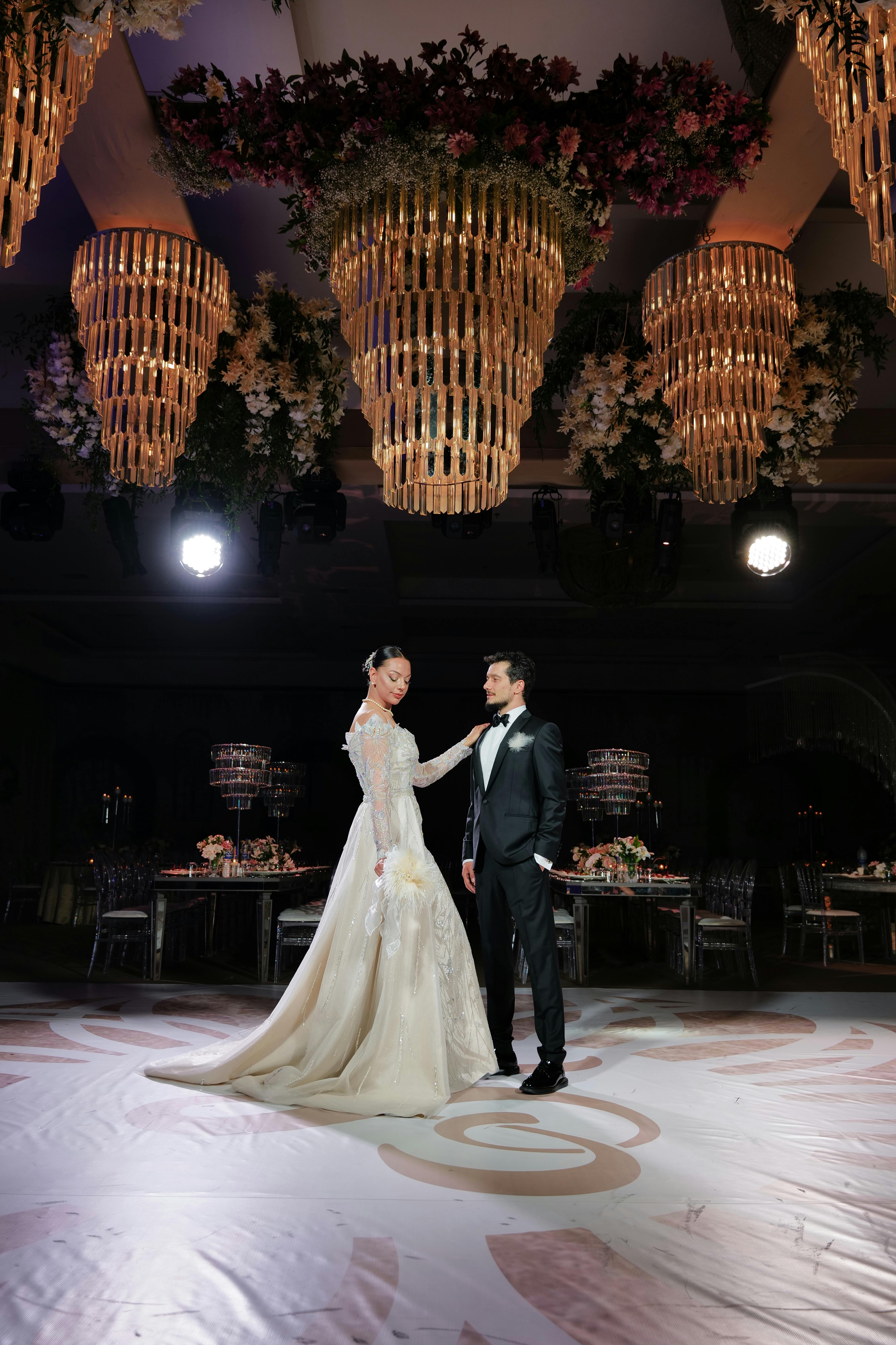 A couple poses in a luxurious ballroom with chandeliers in Denizli, Türkiye.