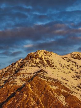 Captivating snow-covered mountain peak under vibrant sky in Türkiye during sunset.