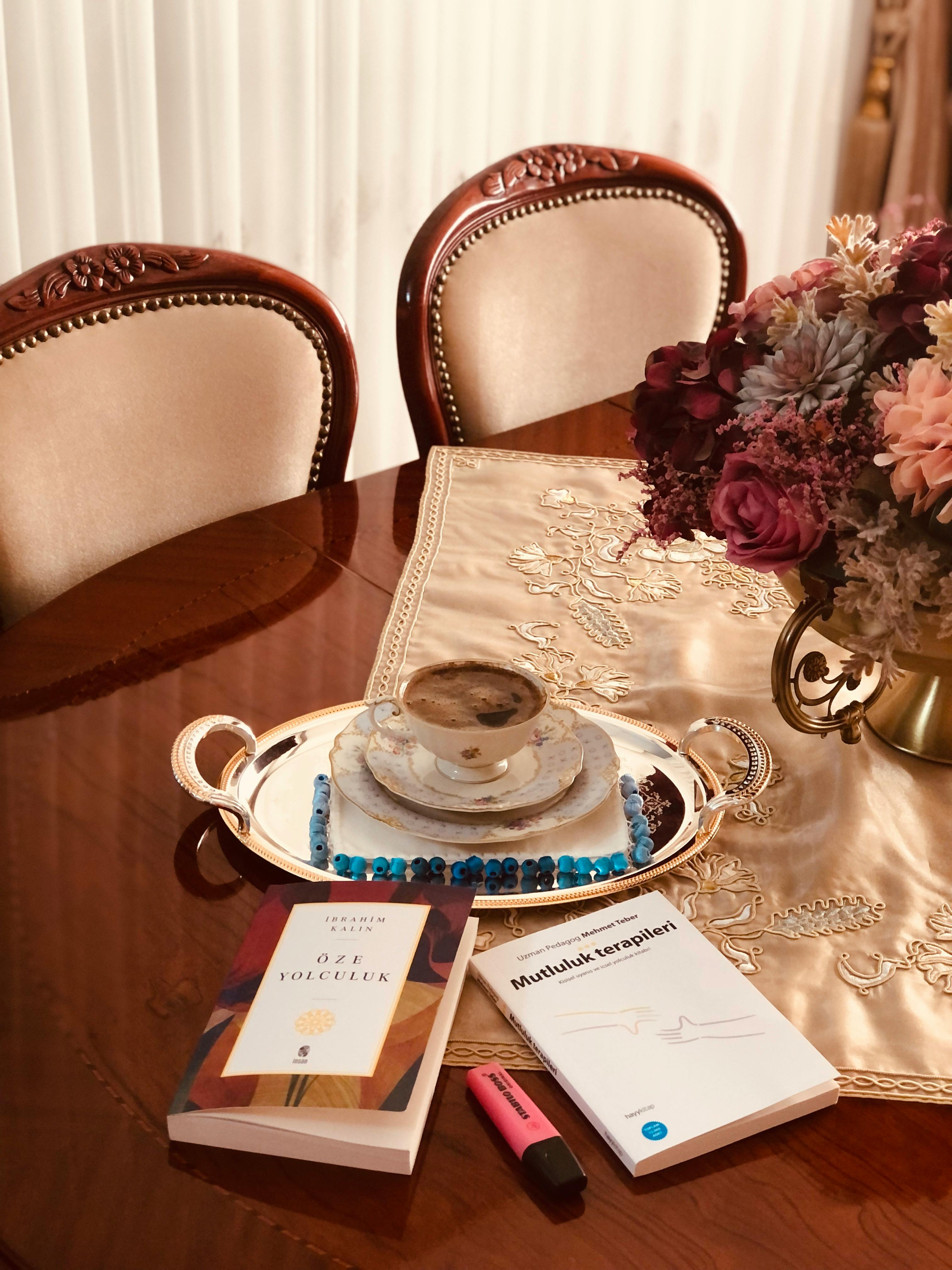 Elegant table setting with a coffee, books, and flowers, creating a cozy atmosphere.
