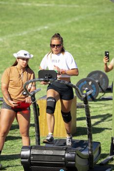 Women exercising outdoors on treadmill and weights during day.