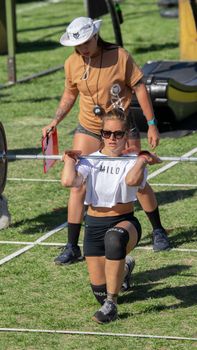 Two women engaged in a CrossFit workout outdoors with a barbell.
