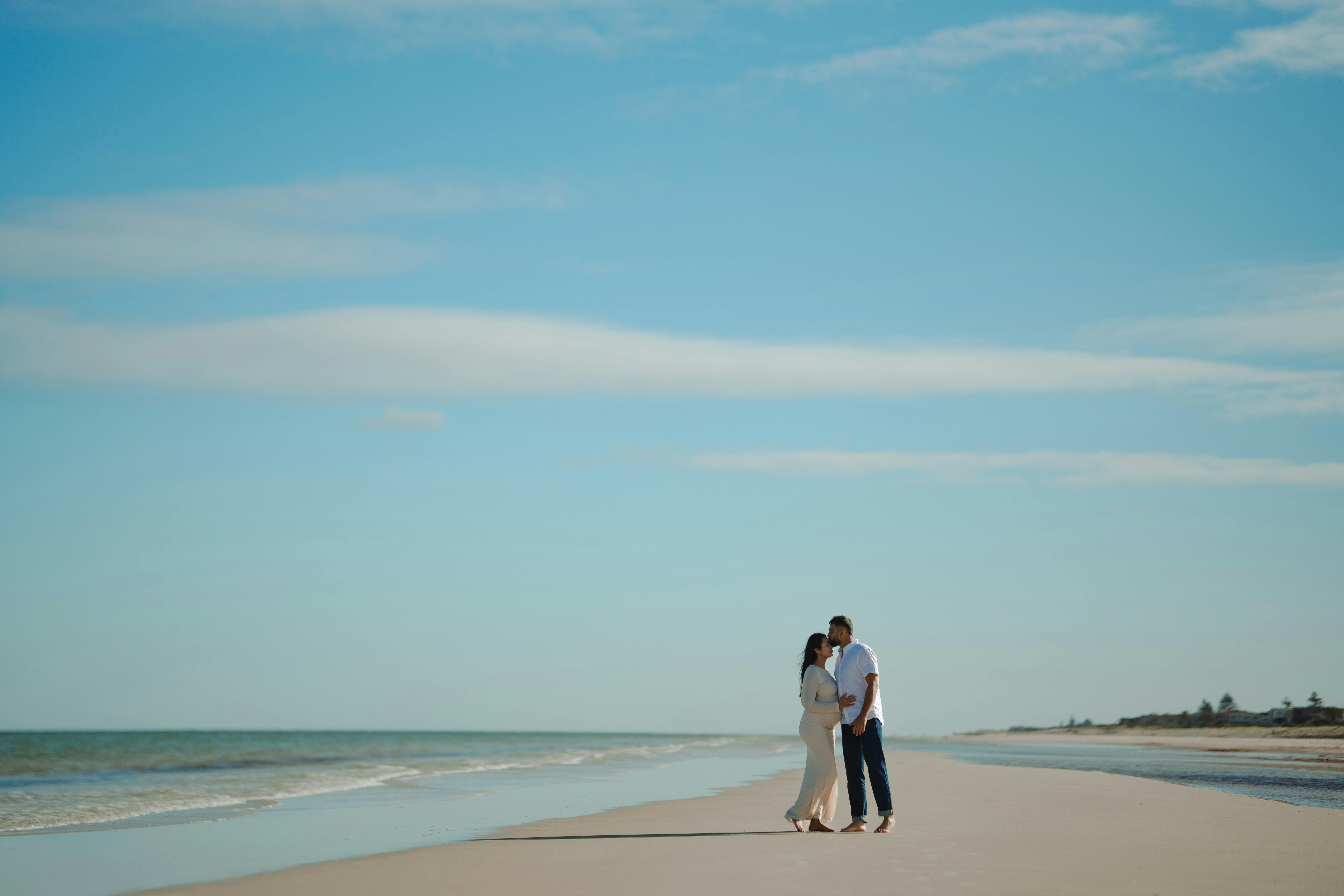 A couple enjoys a romantic walk on a sandy beach in Adelaide, Australia.