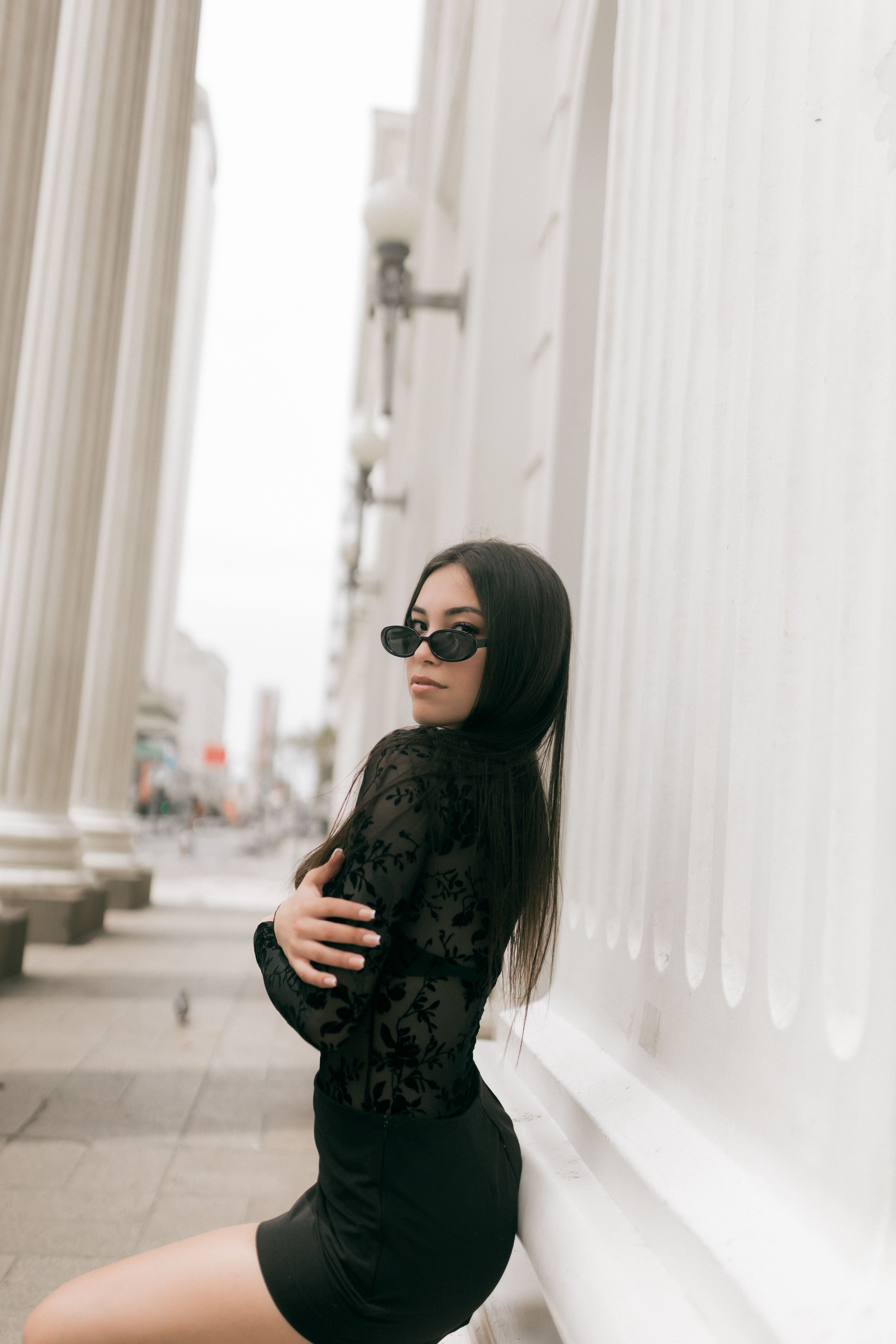 Stylish Woman in Black Outfit Leaning Against Column  Free Stock Photo