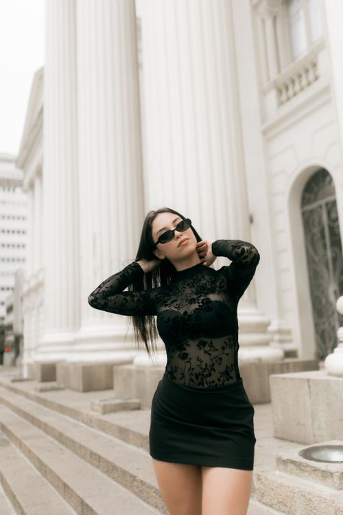 Free Stylish woman in black dress poses by classic architectural columns. Stock Photo