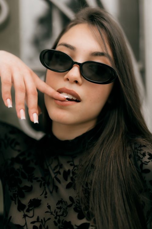 Free Fashionable woman with sunglasses and long hair in a chic outfit poses confidently indoors. Stock Photo