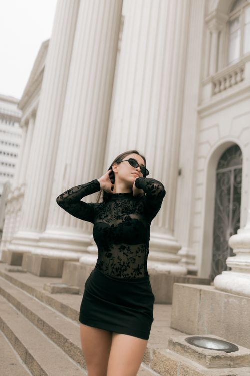 Free Chic woman in stylish black dress poses confidently near classical architecture. Stock Photo