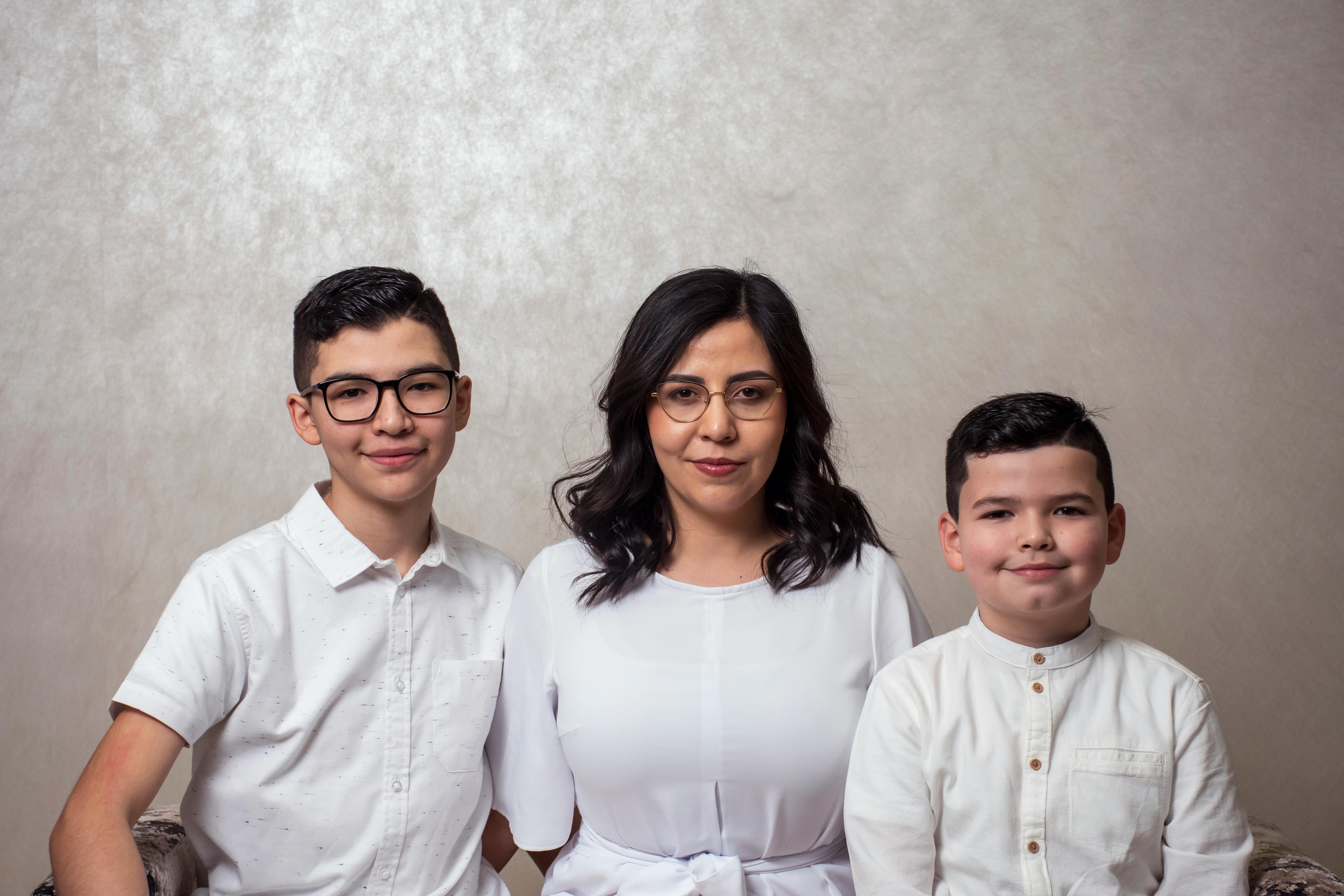 A woman is sitting at a table holding a pen and notebook and looking out the window.