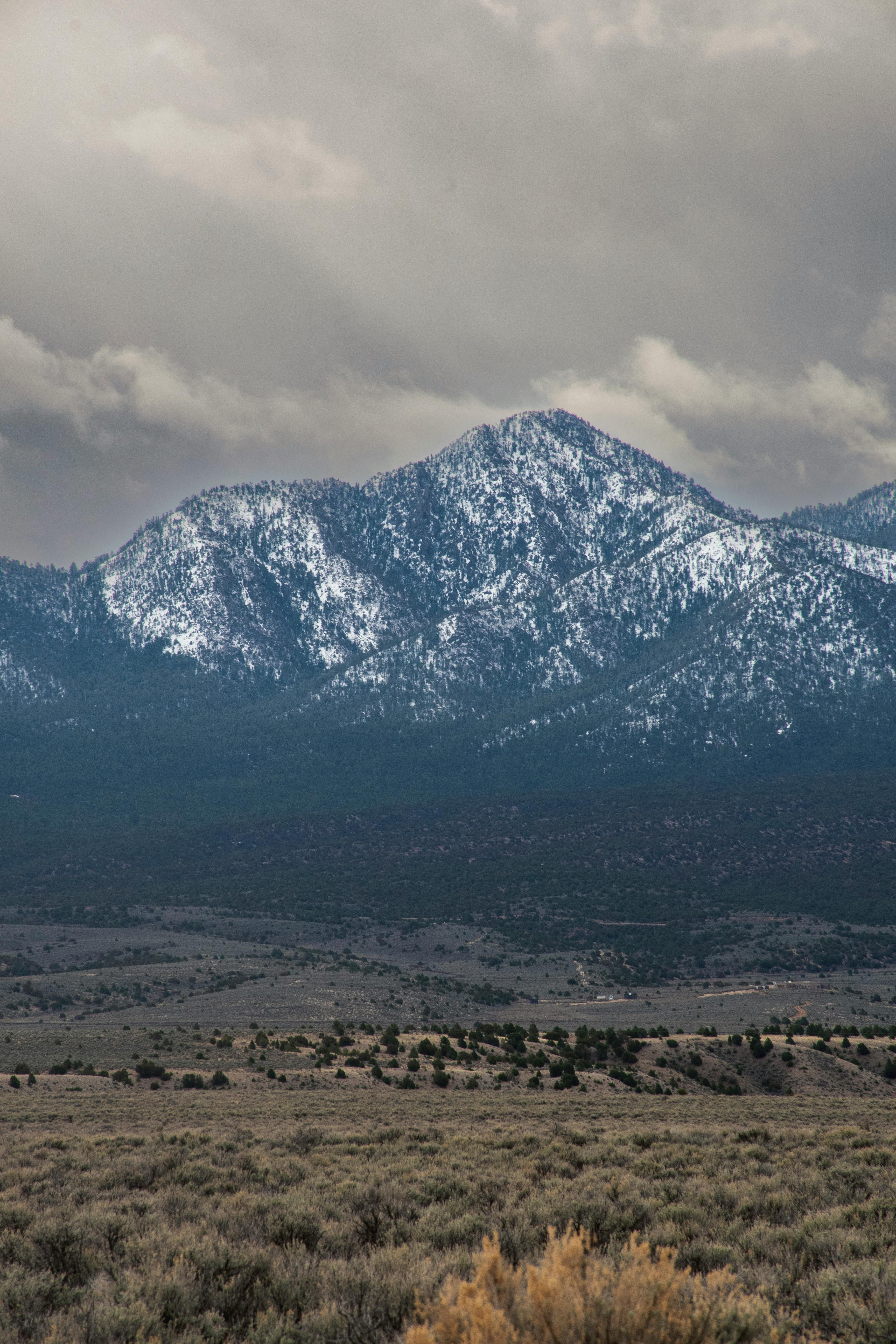 Beautiful snow-capped mountain under cloudy sky with vast rocky terrain.