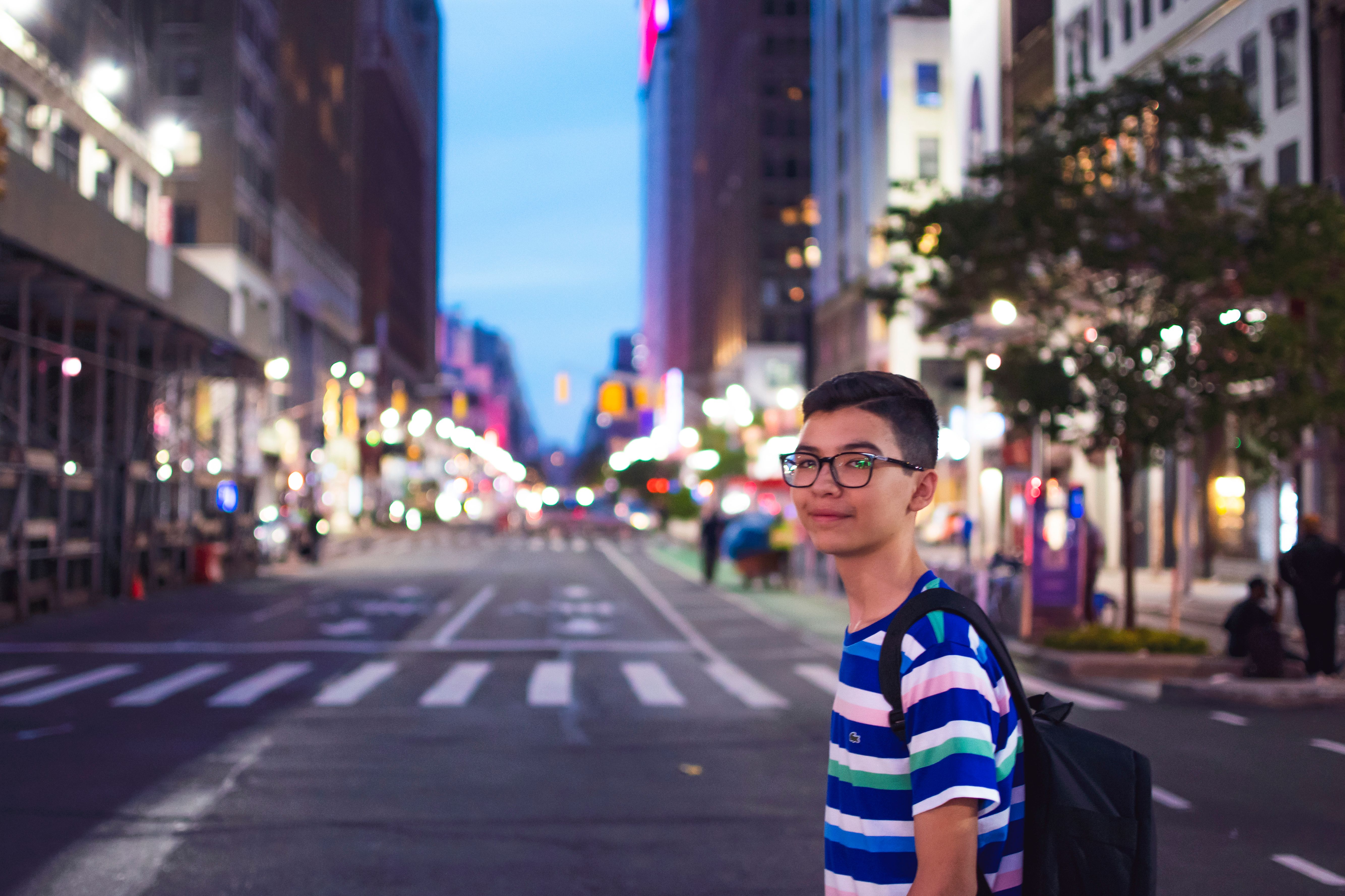 Young man on vibrant city street at twilight · Free Stock Photo