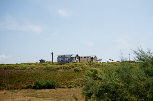 A small house on a grassy hill under a clear blue sky, evoking serenity.