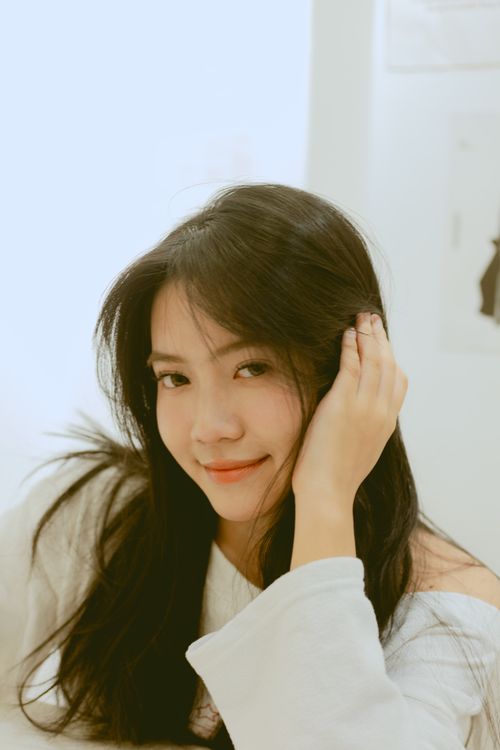 Free Charming portrait of a young woman with long hair, smiling softly in a serene indoor setting. Stock Photo