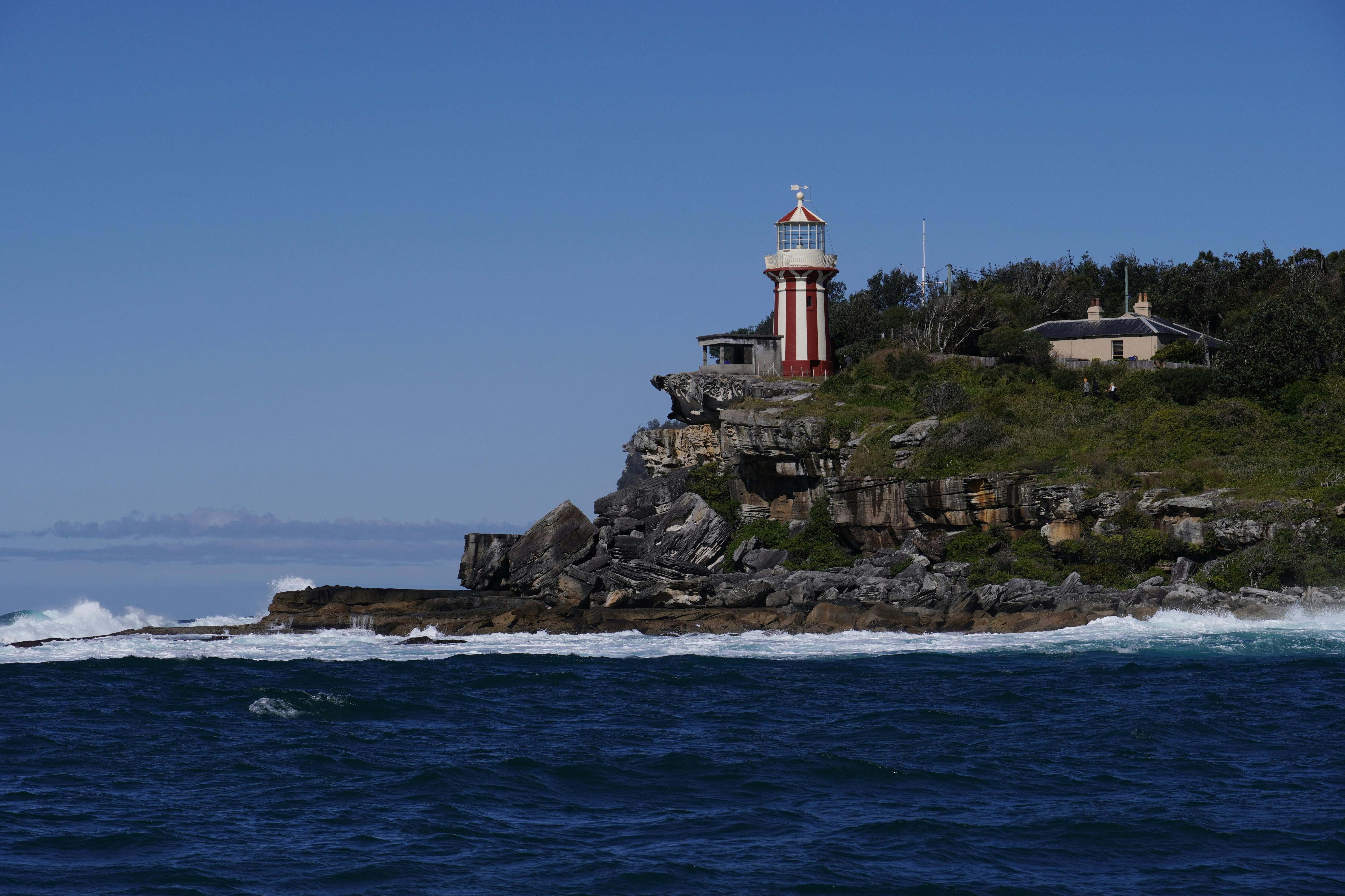 Dramatic view of Hornby Lighthouse perched on Sydney's rocky coastline under a clear blue sky.