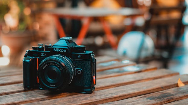 A classic Nikon camera sits elegantly on a rustic wooden table in an outdoor cafe setting.